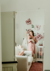 a woman in a pink dress standing in front of a baby's nursery