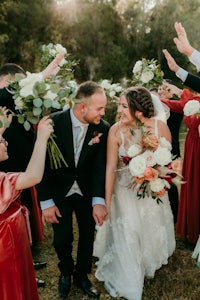 a bride and groom are waving their bouquets in the air