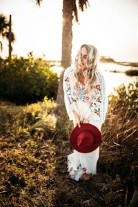 a woman wearing a red hat in front of a palm tree